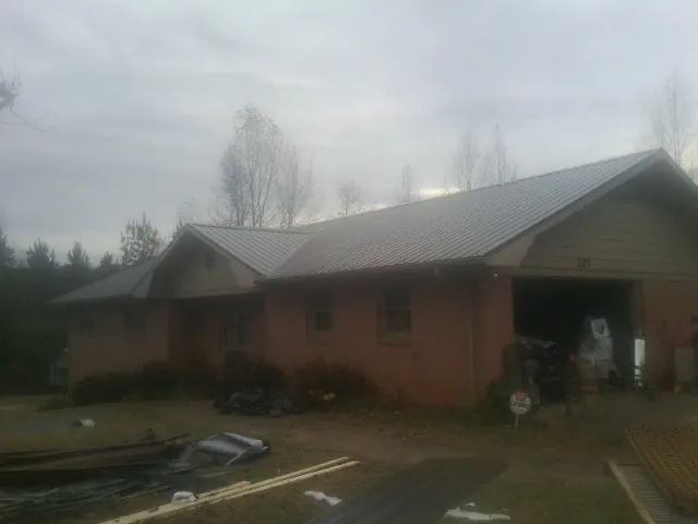 Gray metal roof on a stucco house with an attached garage in Flat Rock
